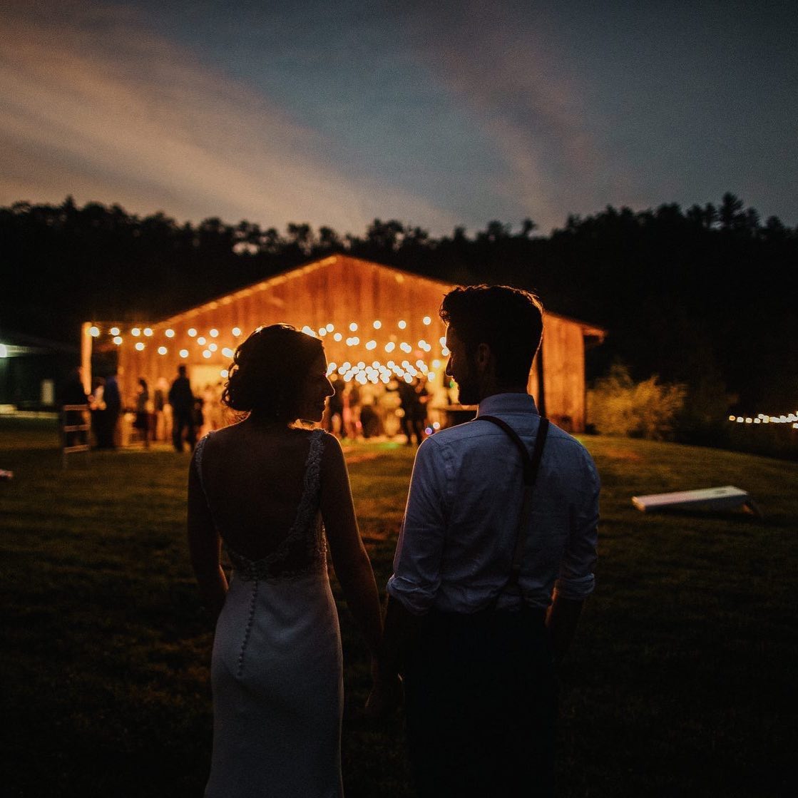 A silhouette of a bride and groom standing holding hands during the night time