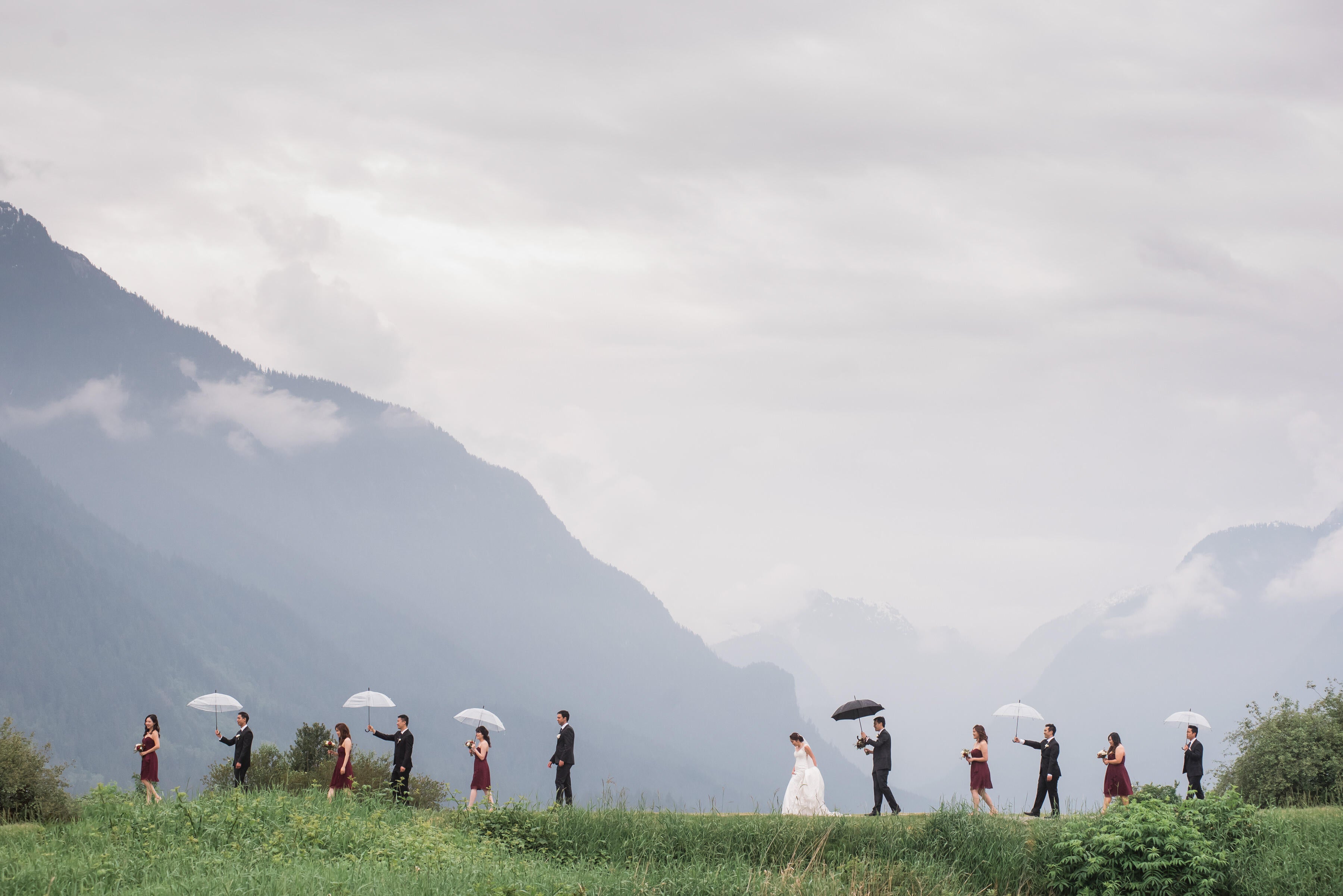 bridal party walking in rain with umbrellas