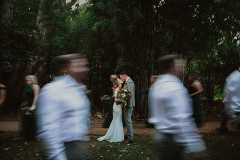 Bride and groom kissing at an open space with bridesmaid and groomsmen acting as a blurred frame 