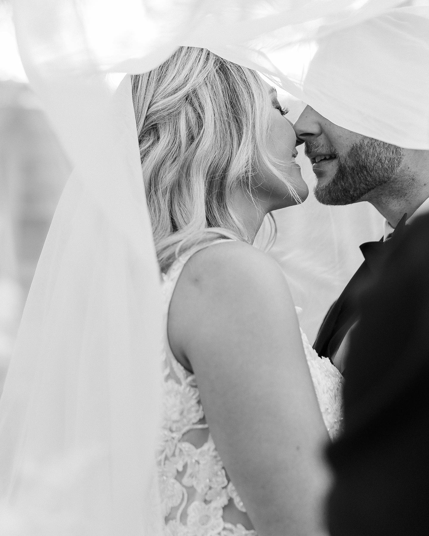 a couple sharing an intimate moment under the wedding veil in their wedding attire