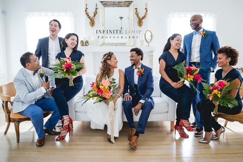 A bride and groom sitting at the center of the couch while the bridesmaid and groomsmen surround them 