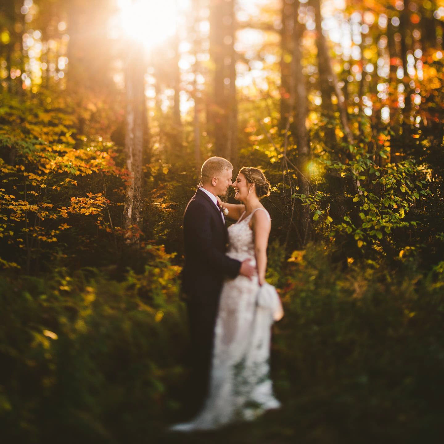 a couple standing in their wedding attire holding each other amidst lush greenery