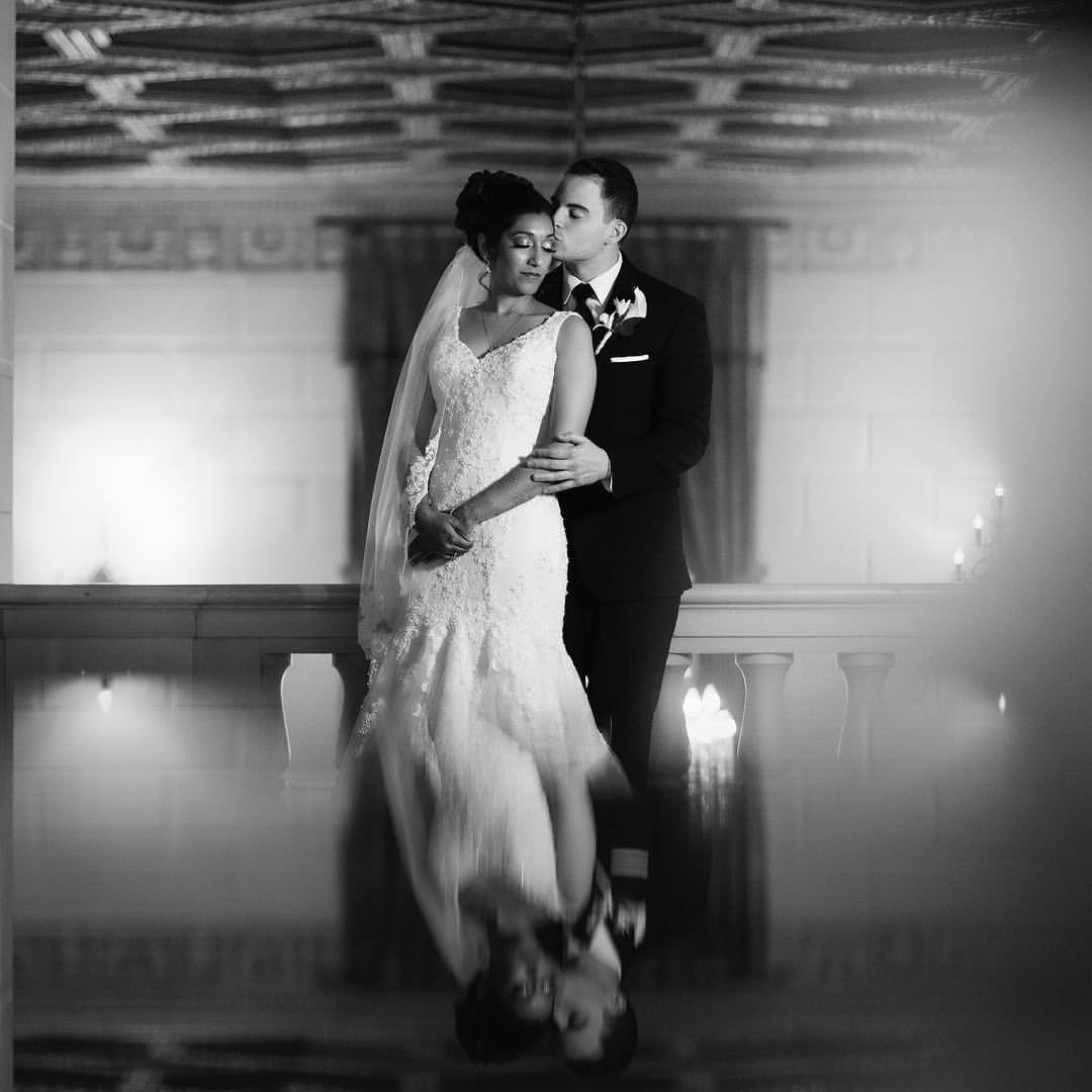 a wedding groom embracing the bride from behind both in their wedding attire