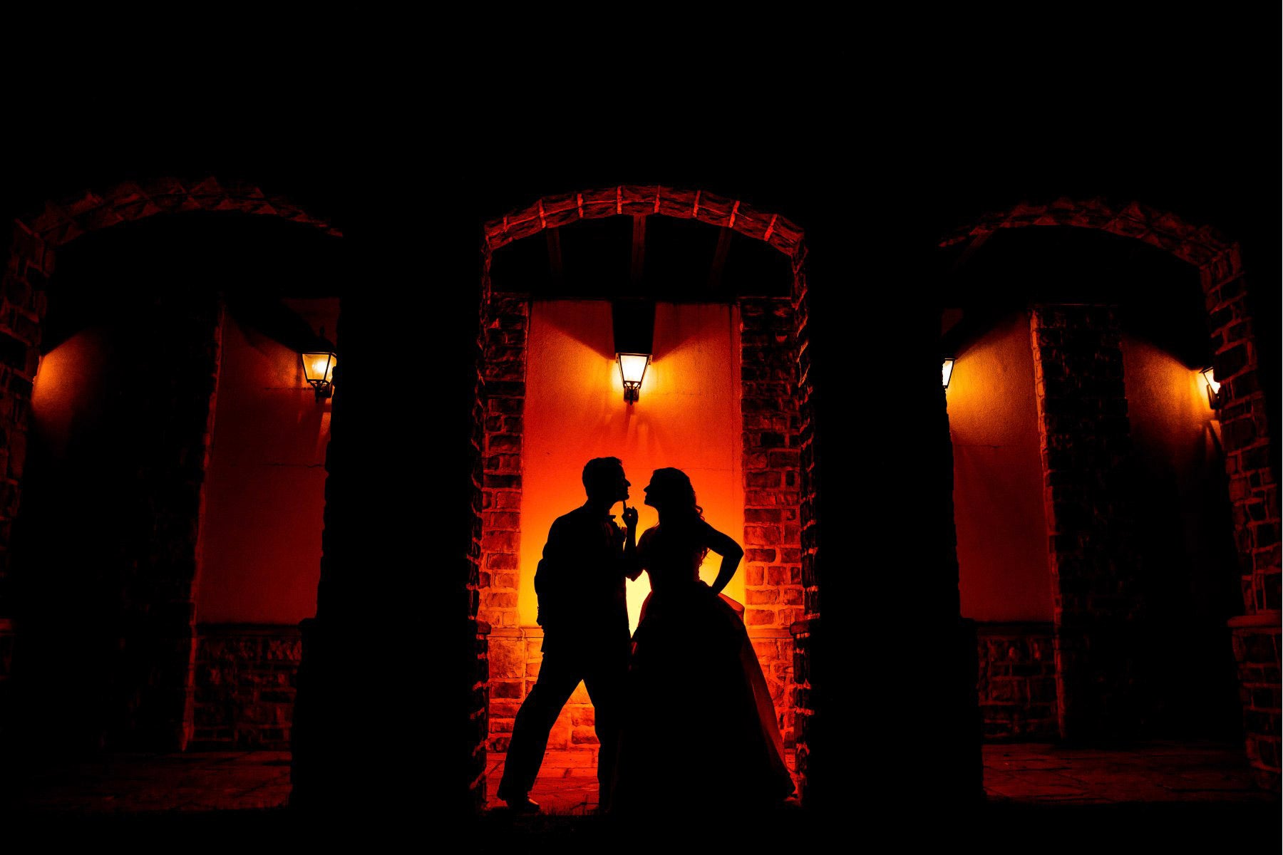 a silhouette of a couple standing together posing in a lowlight setting