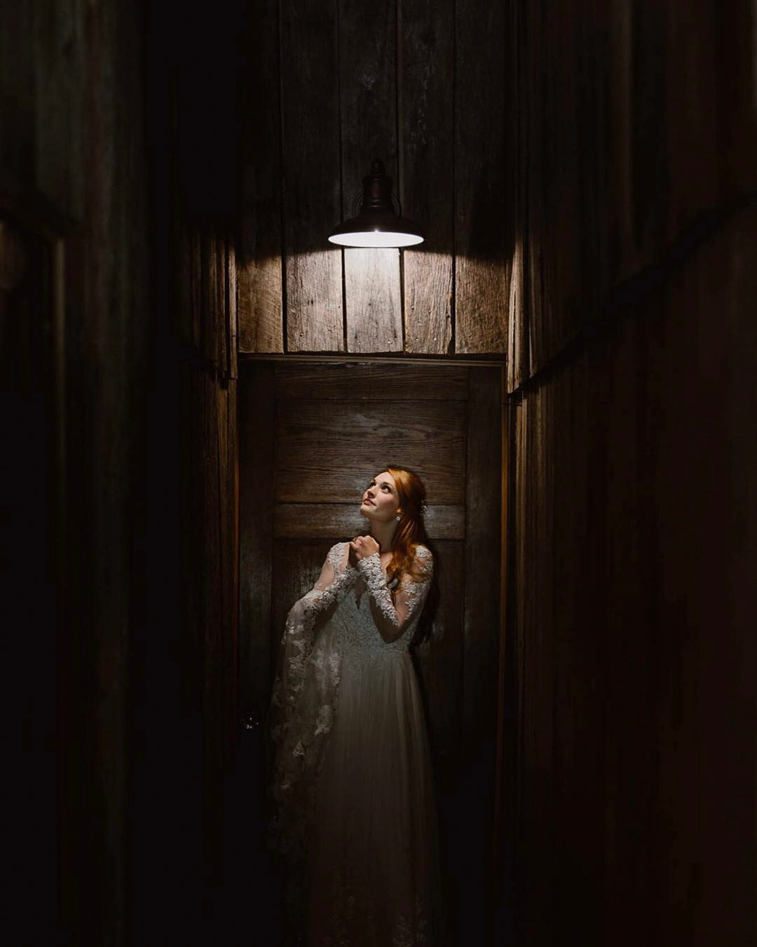 a wedding bride looking up at a ceiling light in a dimly lit room