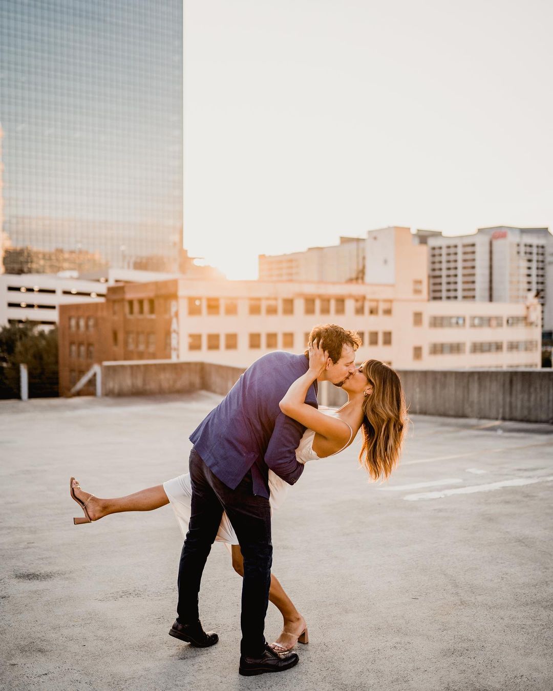 a groom dipping the bride and kissing her on a rooftop  