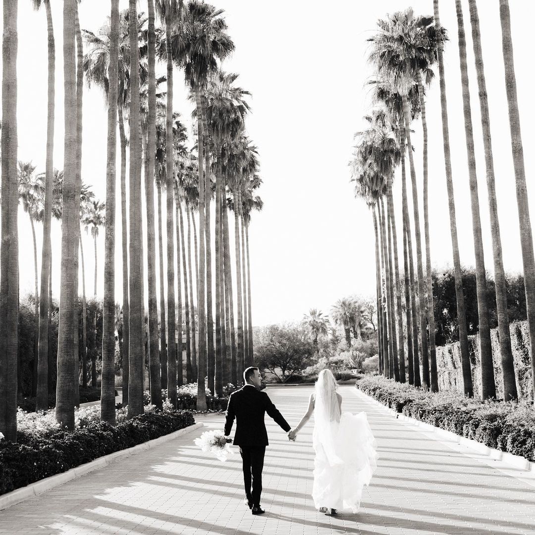 a couple in their wedding attire walking through the middle of the street holding hands 