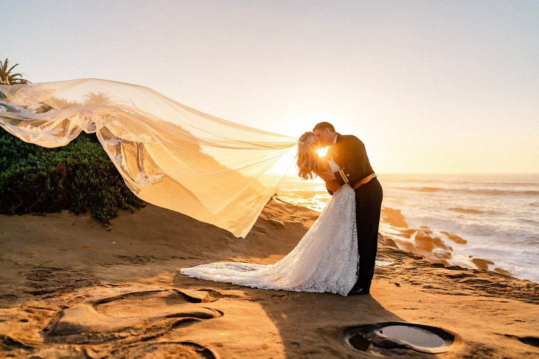 a wedding couple kissing on the beach in a dipping pose