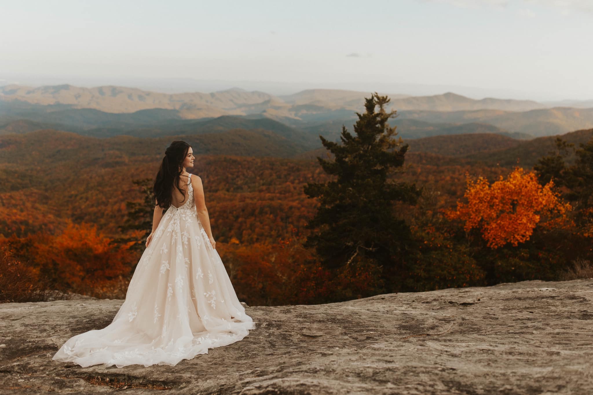 a bride standing on the end of a cliff in her wedding attire