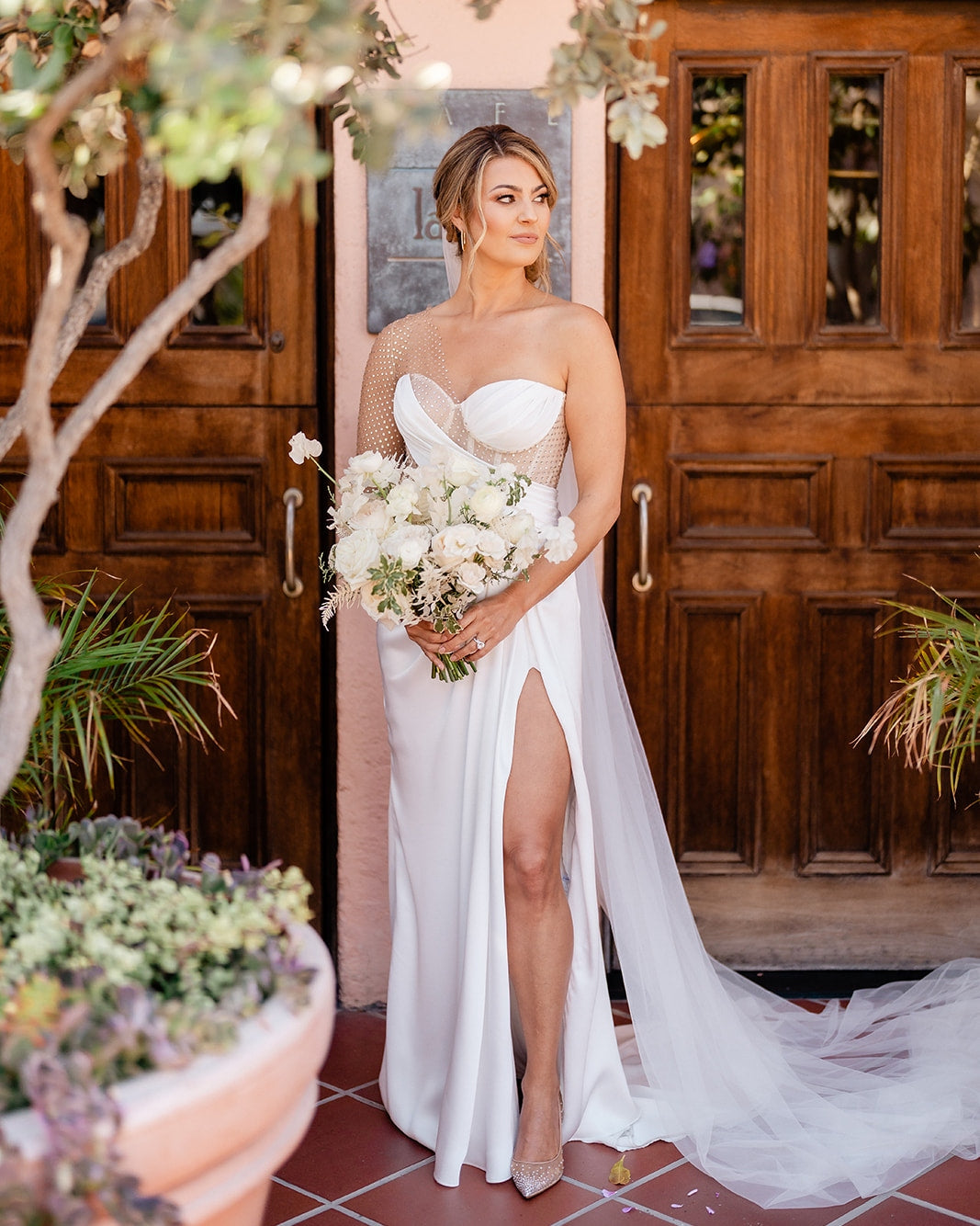 a bride posing in her wedding dress with the wedding bouquet in her hand