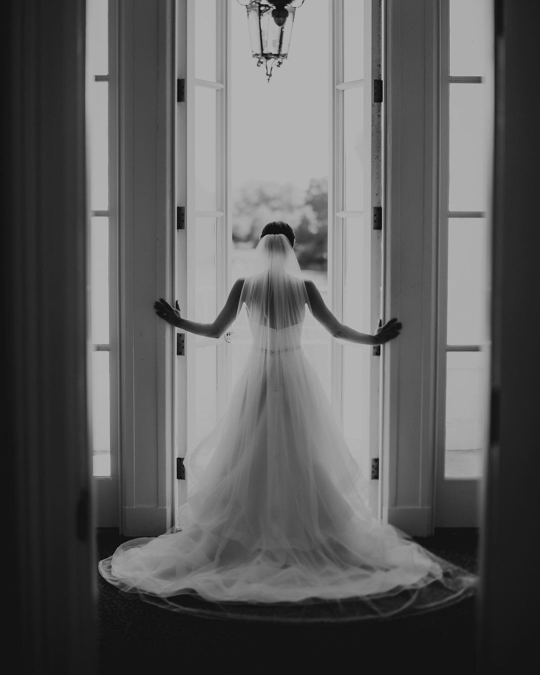 the backshot of a bride in her wedding dress opening a door