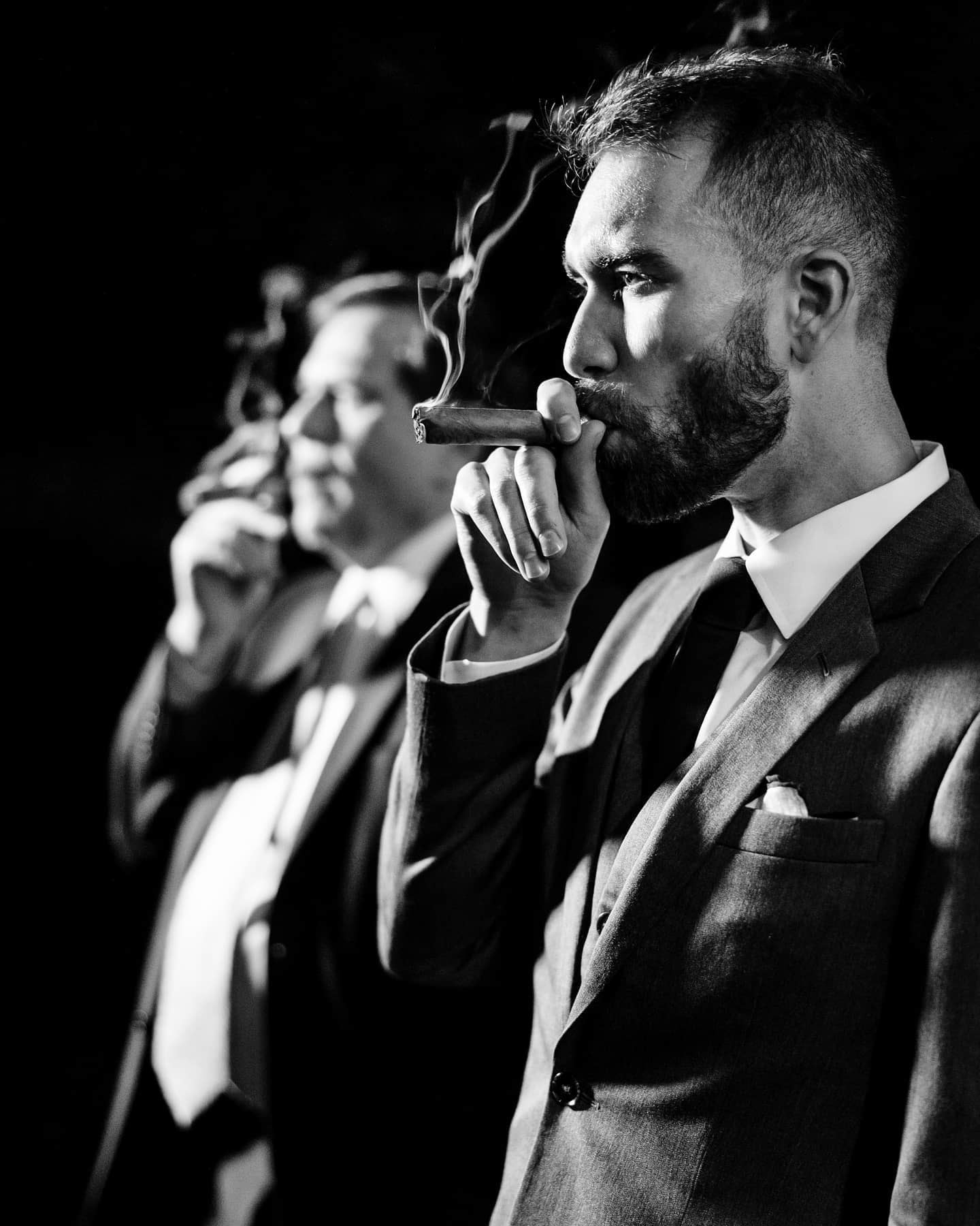 the groom and the groomsmen smoking a cigar in their wedding attire