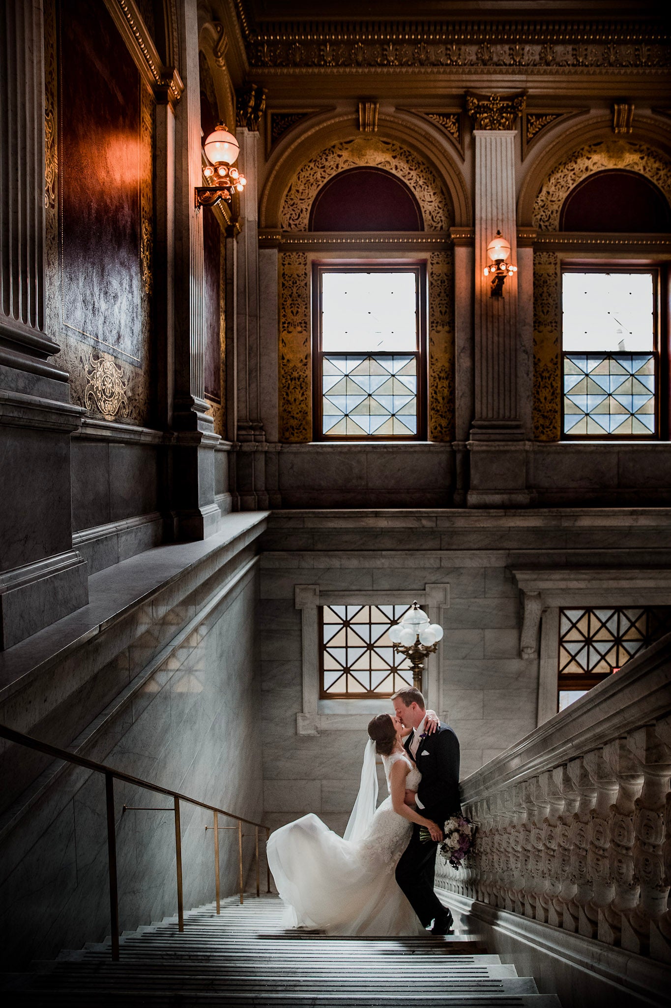 a couple in their wedding dress standing on the stairs of a cathedral