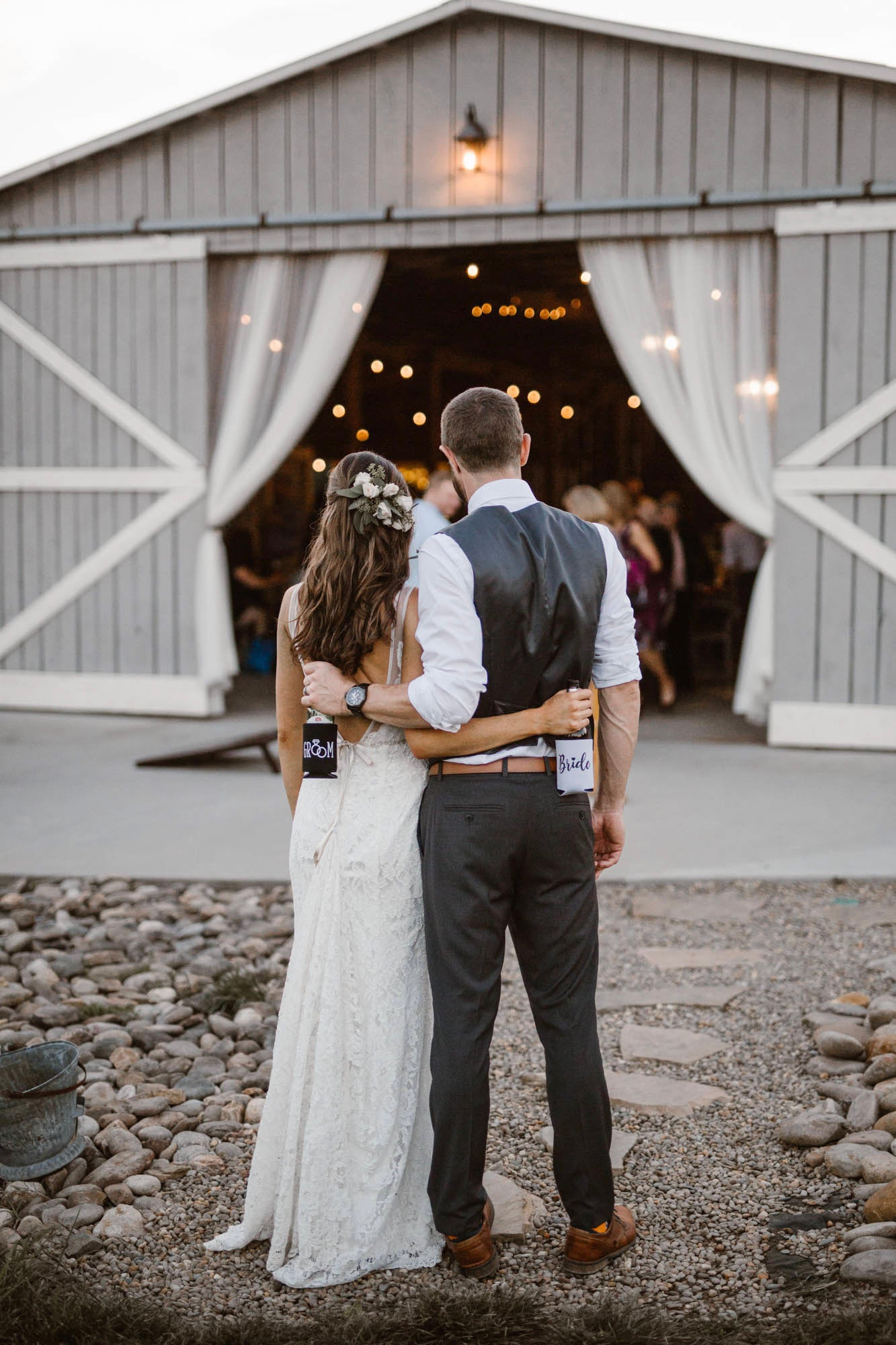 a newlywed couple standing in front of their reception holding each other 