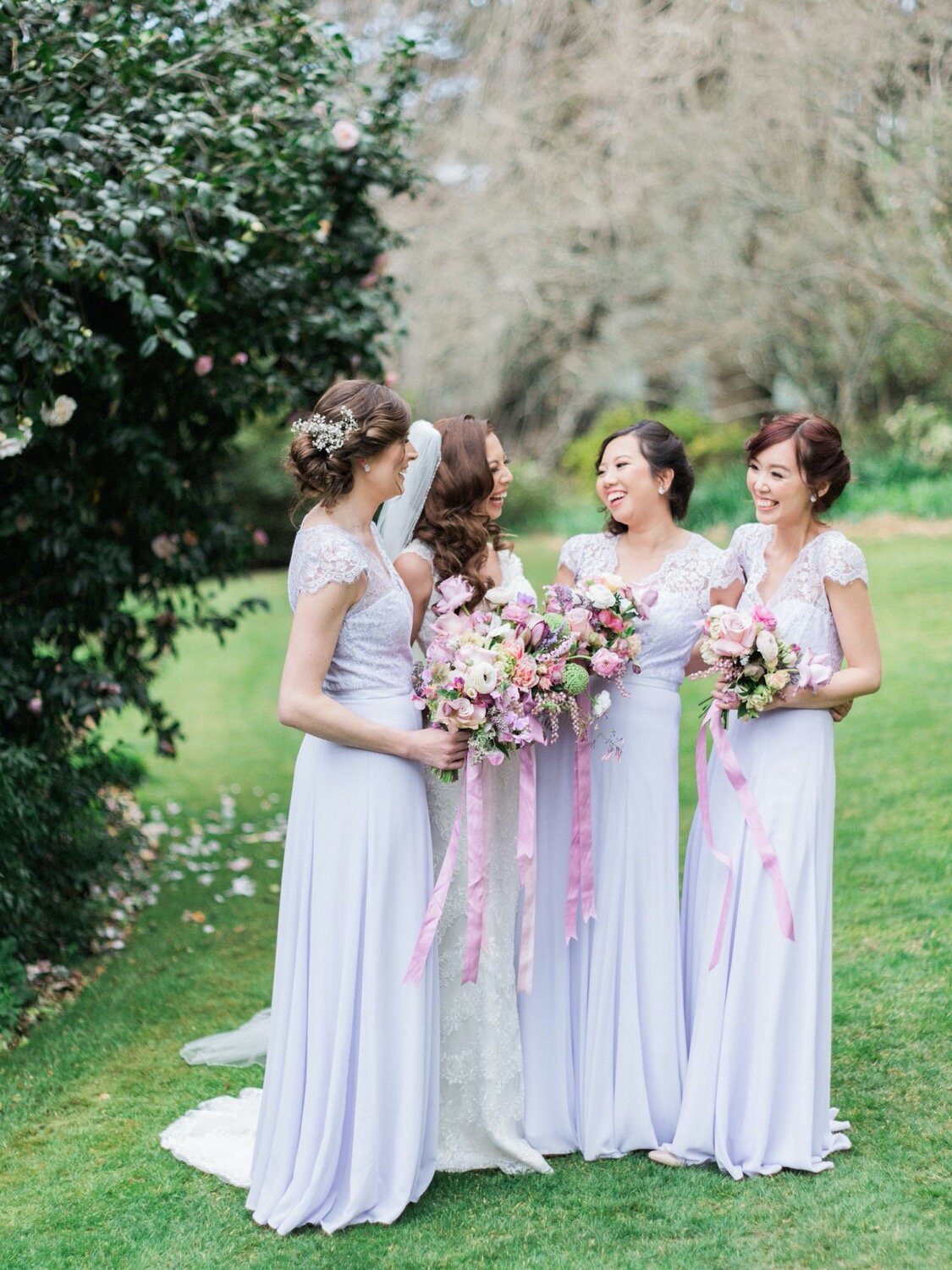 bride with bridesmaids laughing holding bouquets at milton park