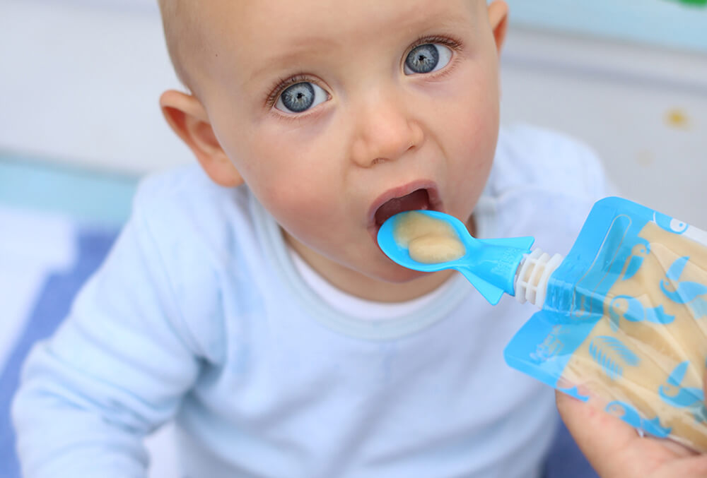 baby feeding from spoon and reusable pouches