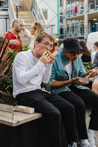 Two men enjoy street food during A Willy Nice Day at Two Tribes CAMPFIRE