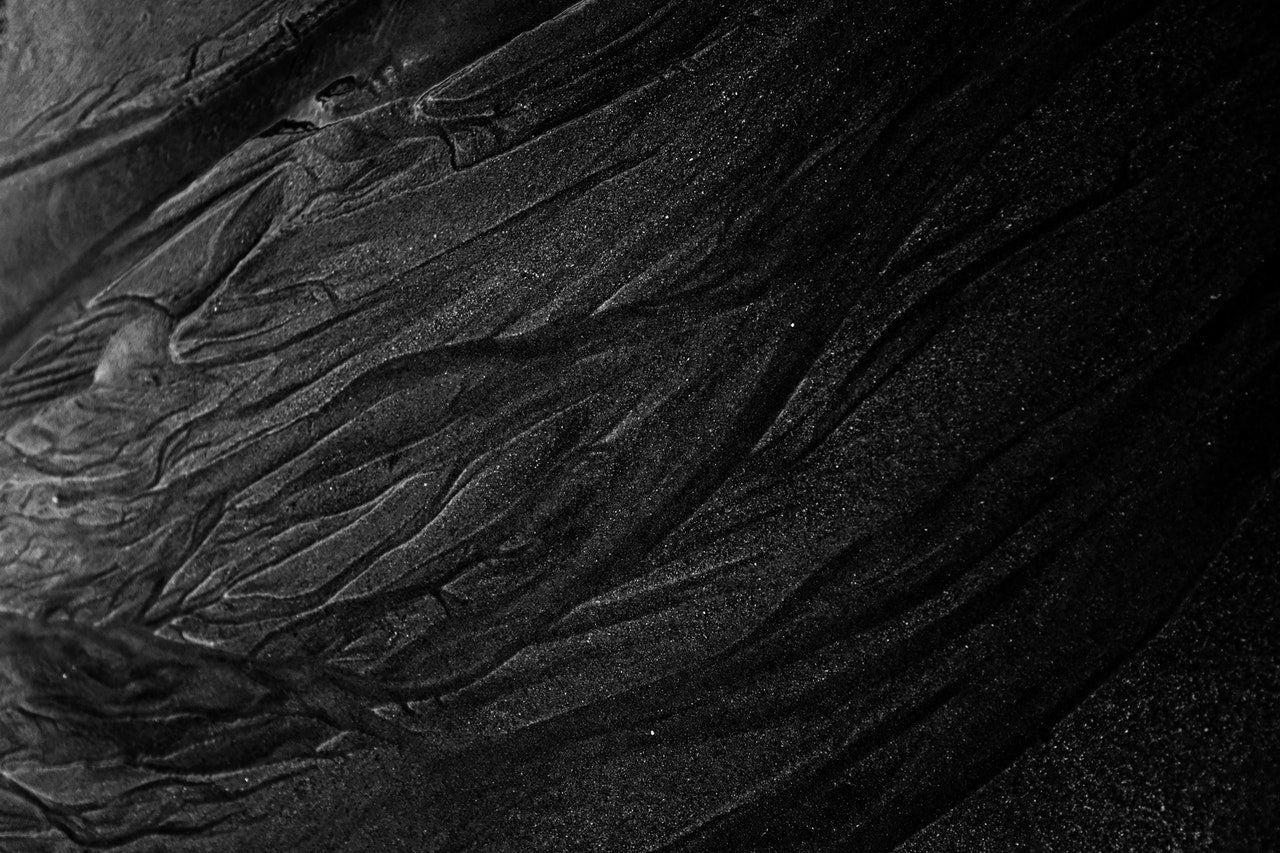 Rough dark sand of shallow river by Adrien Olichon