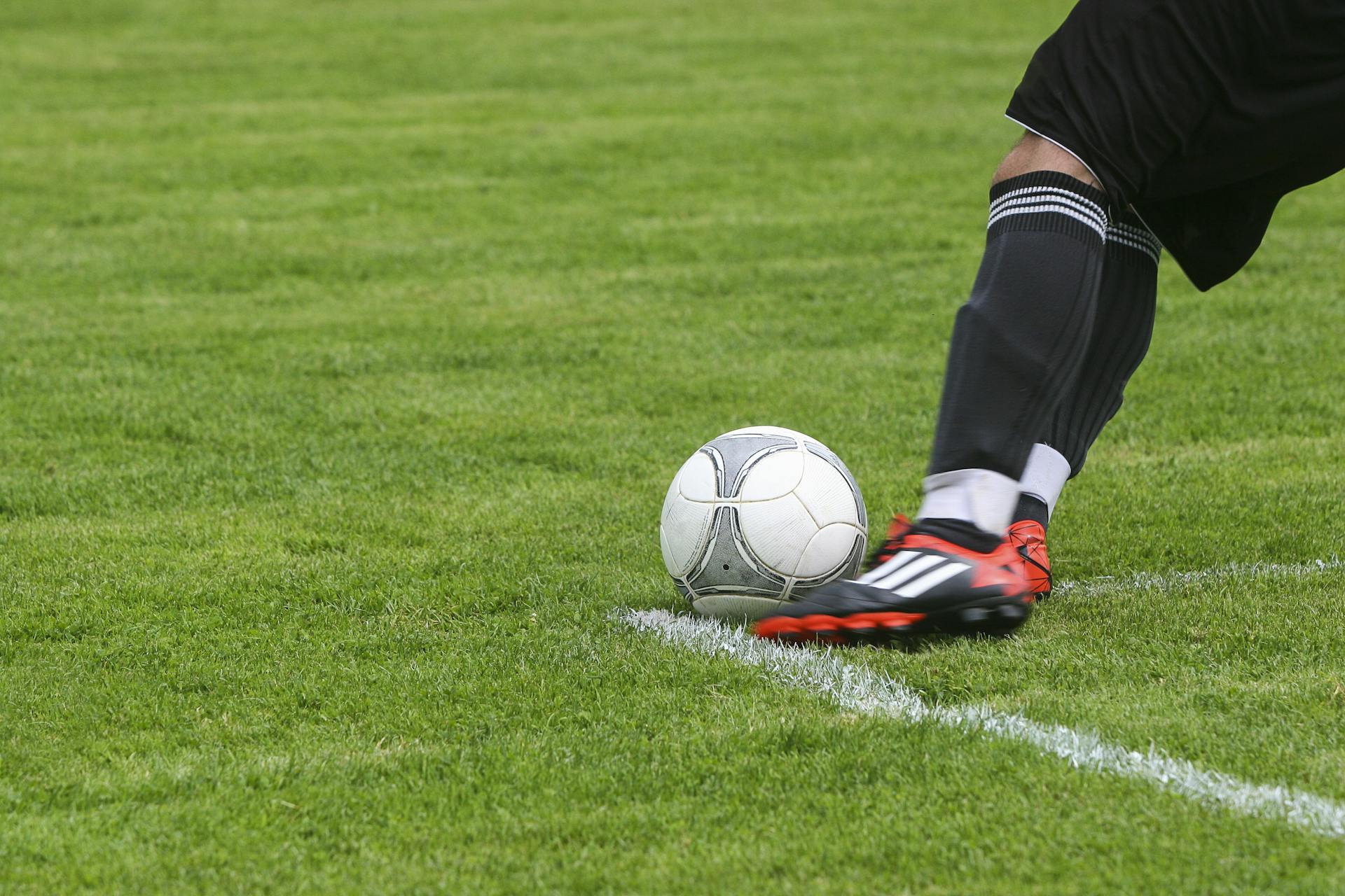 Soccer Player Kicking White Gray Soccer Ball on Green Grass Field by Pixabay