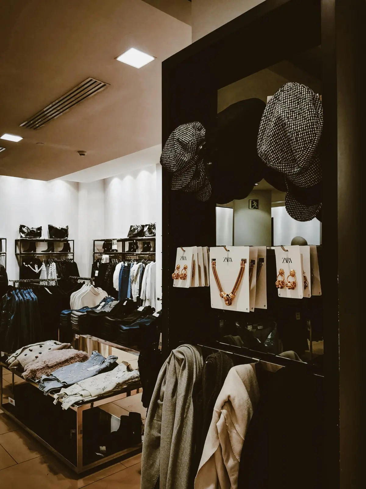 Interior of a clothing store with racks of garments, folded clothes, and displays featuring
