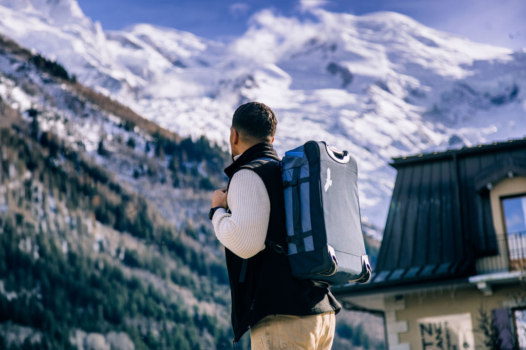Staring at the snowy alps with a carry-on backpack