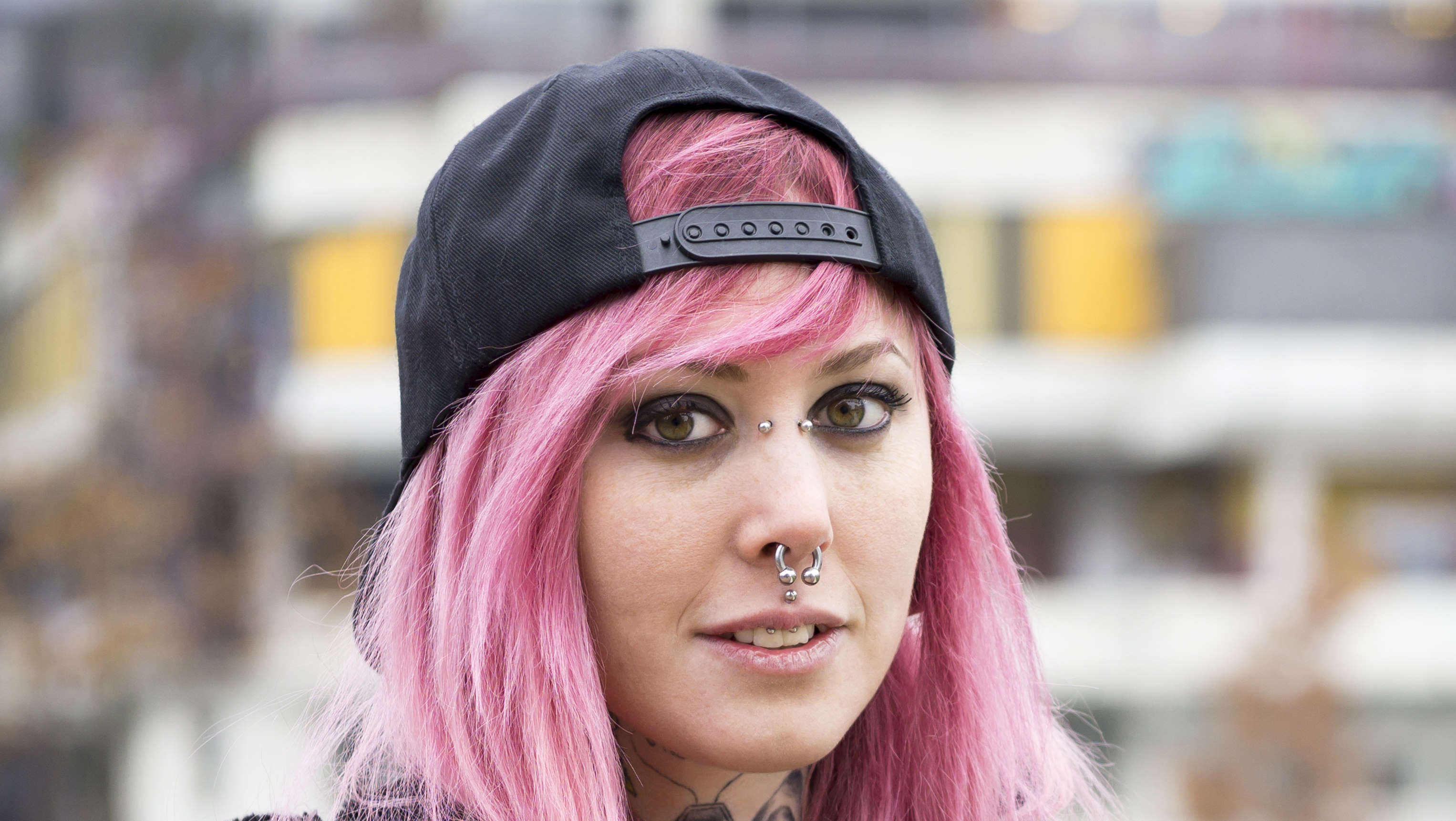 A female with pink hair along with a bridge piercing, septum piercing, and medusa piercing.