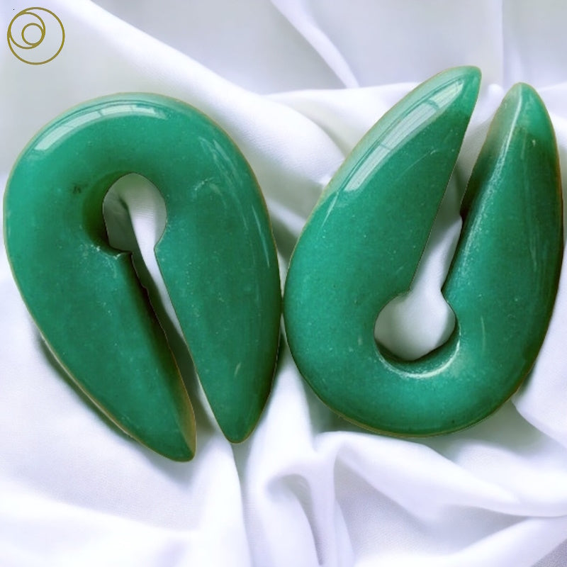 Green stone hangers pictured against a white fabric background.