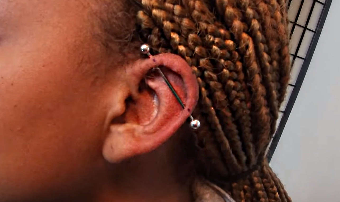 A female with a piercing that has a surgical steel bar through it.