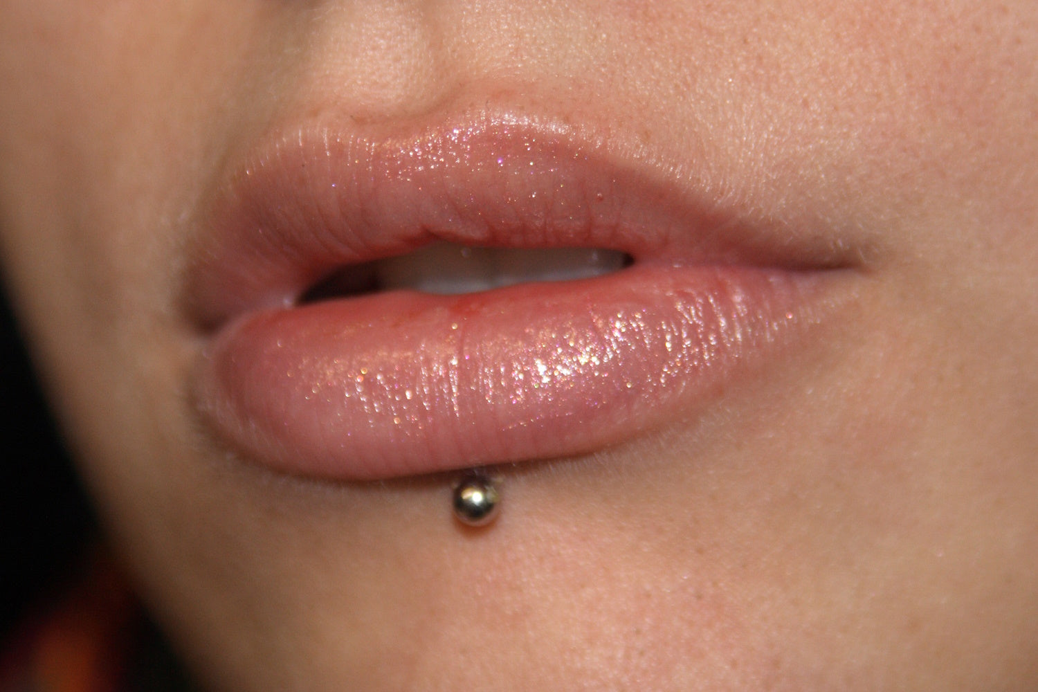 A close up of a female with her lip pierced.