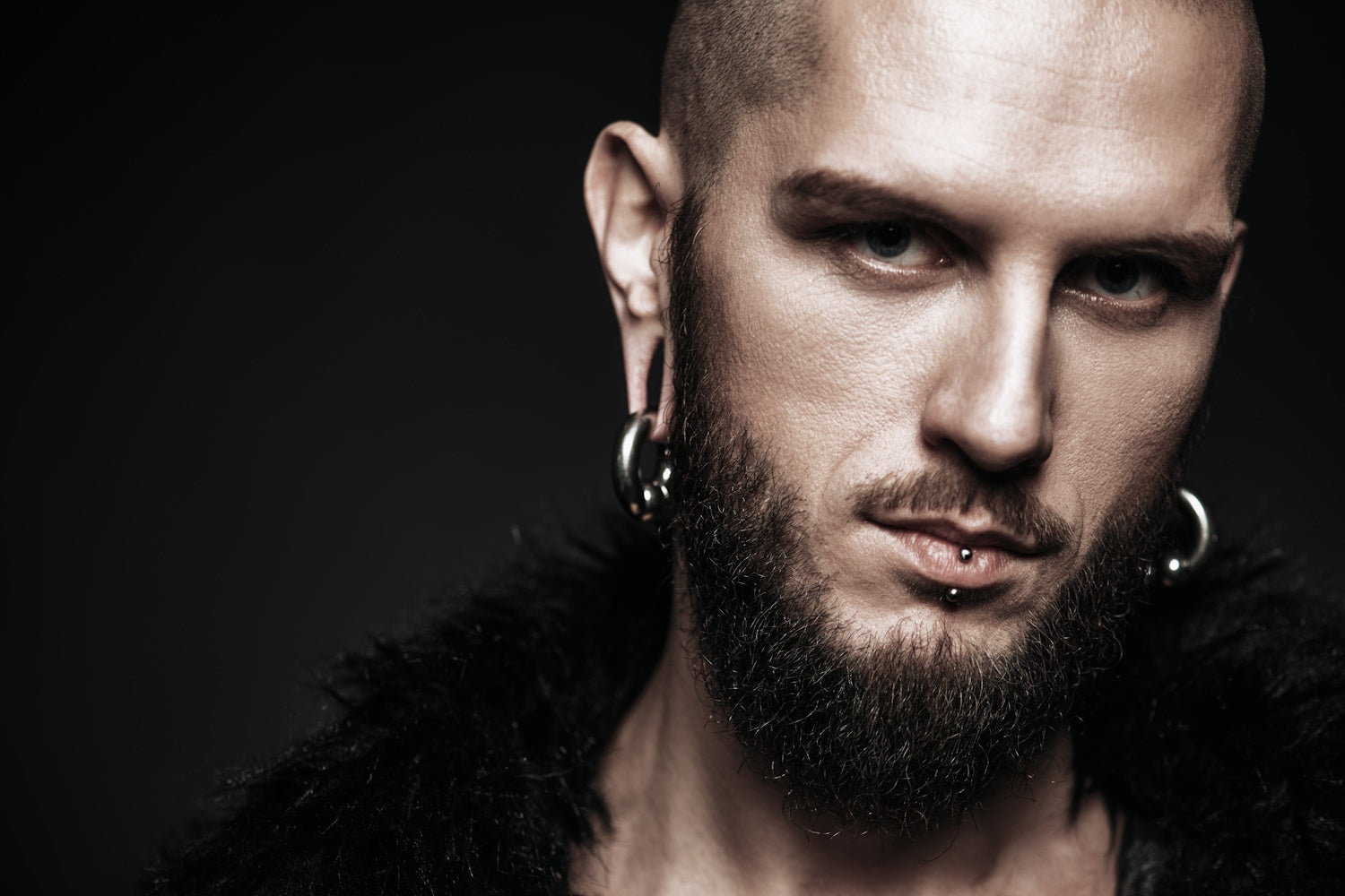 A man with many piercings on his face and ears.