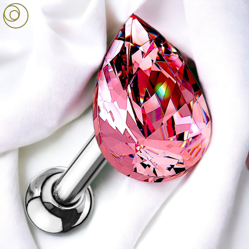 A pink teardrop 16 gauge earring made with a pink crystal that has a surgical steel bar pictured against a white fabric background.