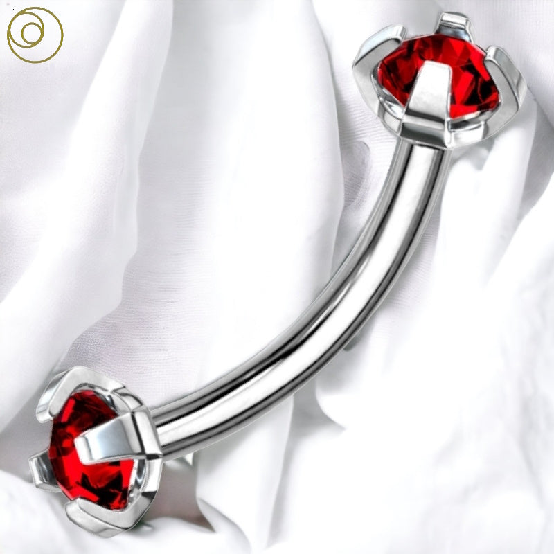 An internally threaded red gem curved barbell with a red gem on each end of a surgical steel curved barbell pictured against a white fabric background.