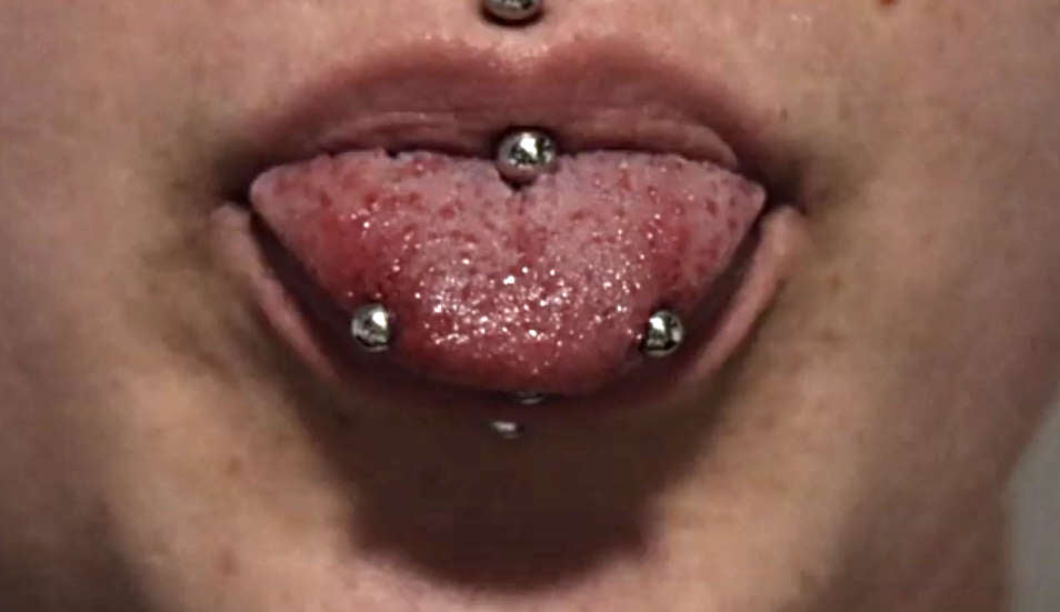 A female showing off her snake eyes tongue piercing example.