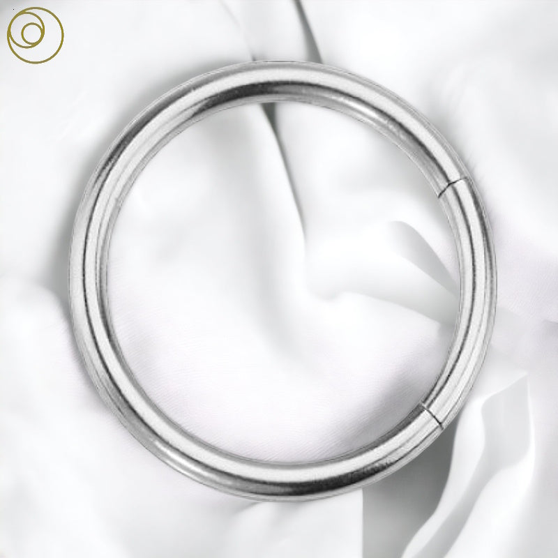 Surgical steel segment ring on a white fabric background.