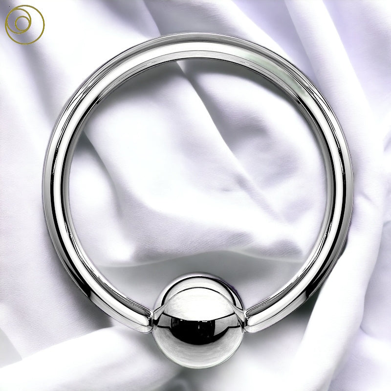 A surgical steel captive bead ring pictured against a white fabric background.