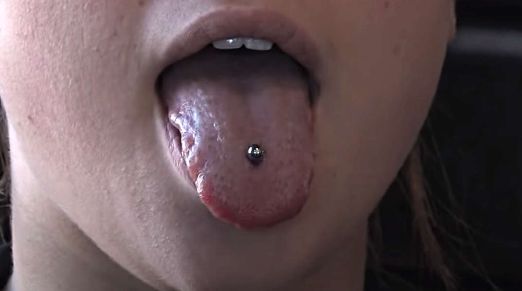 A tongue piercing example showing a female sticking her tongue out drawing attention to her new piercing.