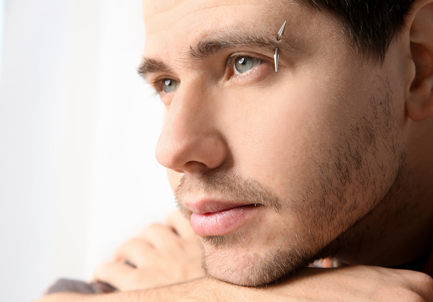 A vertical eyebrow piercing as shown on a man.
