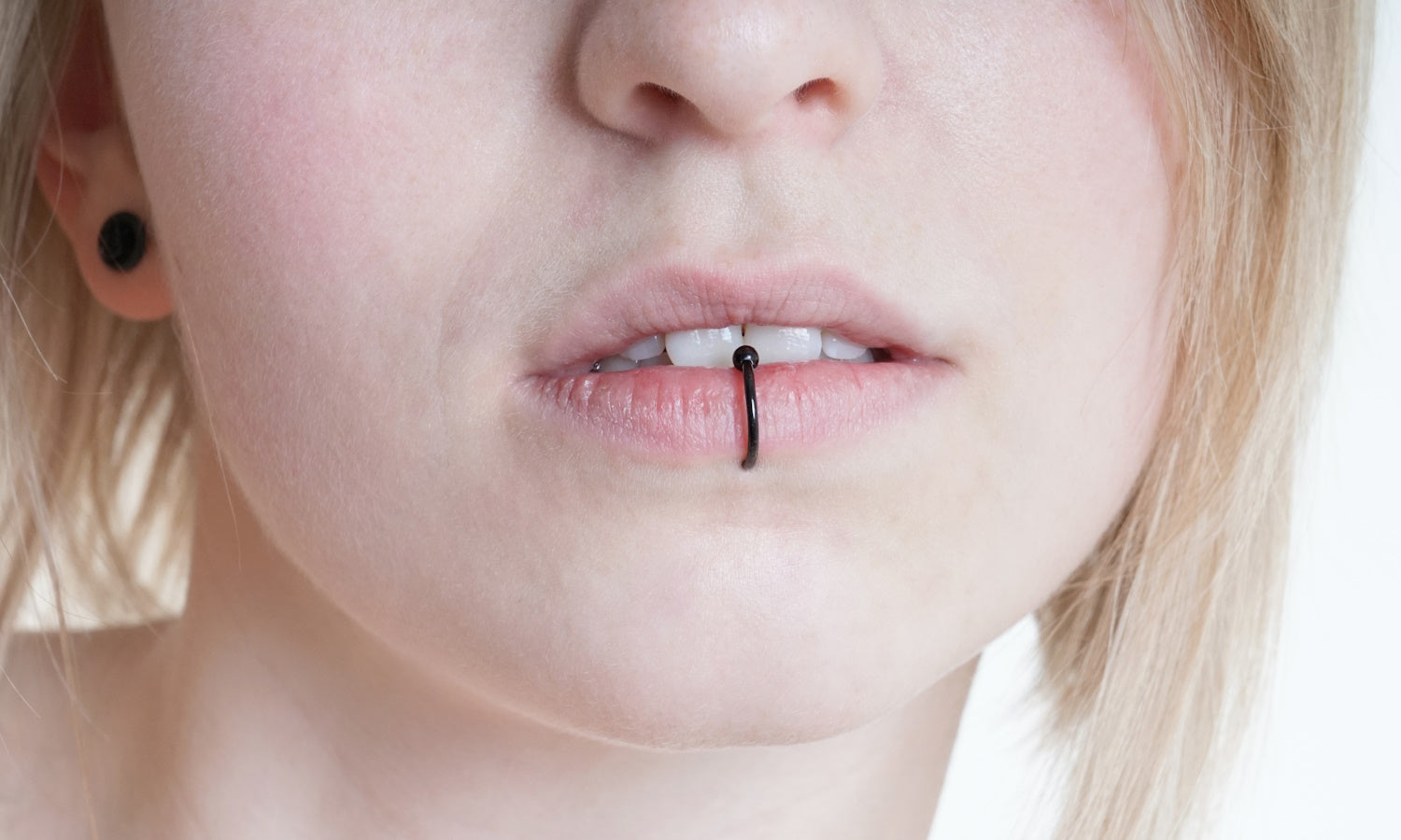 The face of a woman with a black captive bead ring in.