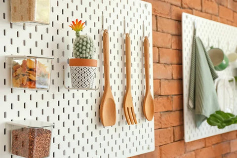 pegboard holding kitchen utensils on a brick wall
