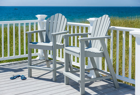 two grey balcony adirondack chairs on a porch over looking the water