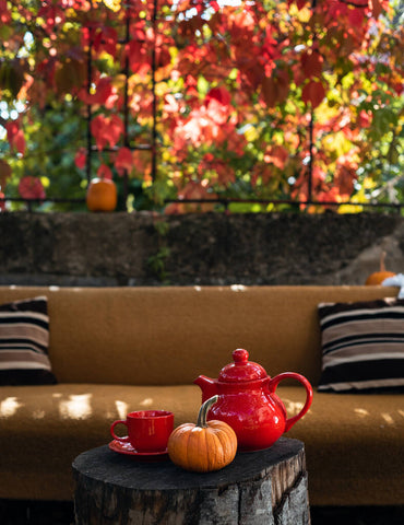 burnt yellow sofa with a floral landscape behind and an autumn themed tea set