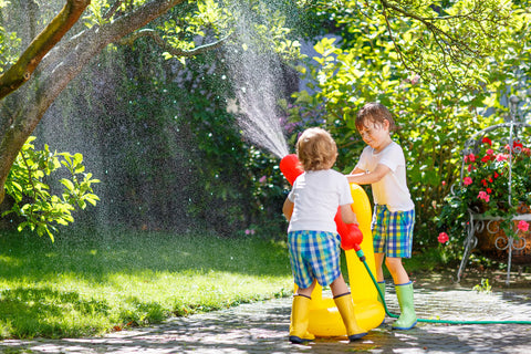 two kids playing with a water hose