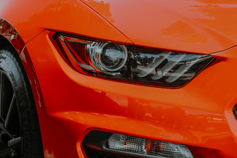 Close-up of an orange sports car's sleek headlight design.