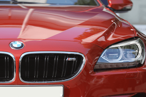 Close-up of a red BMW M5 with a focus on the grille and badge.
