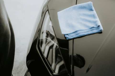 Detailing a car's reflective surface, ensuring care with a gentle cleaning cloth.