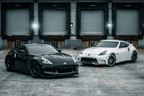 Two Nissan 370Z coupes parked side by side, one black and one white.