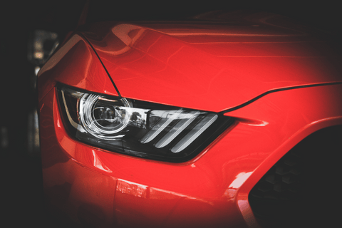 Close-up of a red sports car's headlight with a sleek design.