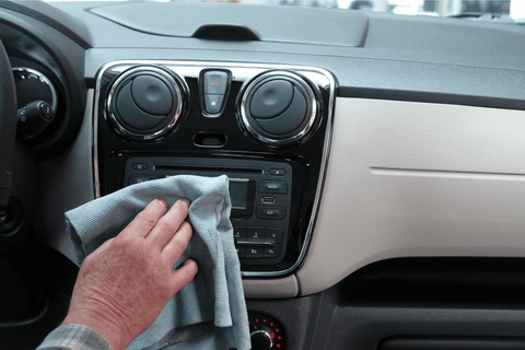 A person cleaning the interior of a car with a microfiber cloth.