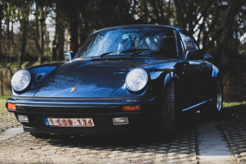 Vintage Porsche 911 in blue under trees.