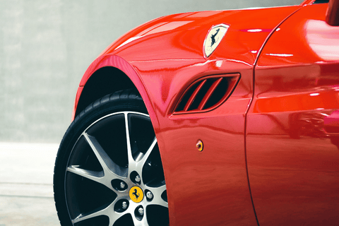 Close-up of a red Ferrari's fender and wheel with the iconic logo.